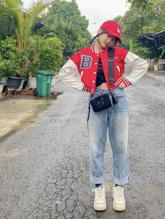 Tante Gala ini tampil sporty dengan jaket basketball merah, dipadukan celana denim. Dengan topi cap merah dan snapshot camera bag dari Marcjacobs hitam seharga Rp4.6 juta. (@fuji_an)
