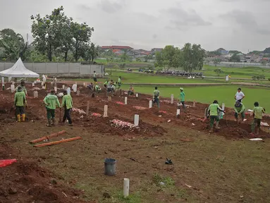 Petugas dengan APD melakukan proses pemakaman dengan protokol Covid-19 di TPU Bambu apus, Jakarta Timur, Minggu (24/1/2021). Empat hari dibuka, 126 jenazah telah dikebumikan dengan protap Covid-19 di TPU Bambu Apus, Cipayung, Jakarta Timur. (Liputan6.com/Herman Zakharia)