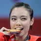 Atlet wushu Indonesia, Lindswell Lindswell menggigit medali emas usai memenangkan kategori wushu taijijian putri Asian Games 2018 di Jakarta, Senin (20/8). (AP Photo/Aaron Favila)
