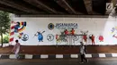 Pejalan kaki melintasi mural Asian Games 2018 yang menghiasi kolong Jembatan Layang Tol Bintaro, Jakarta, Senin (13/8). Mural tersebut untuk sosialisasi dan mendukung Asian Games. (Liputan6.com/Fery Pradolo)