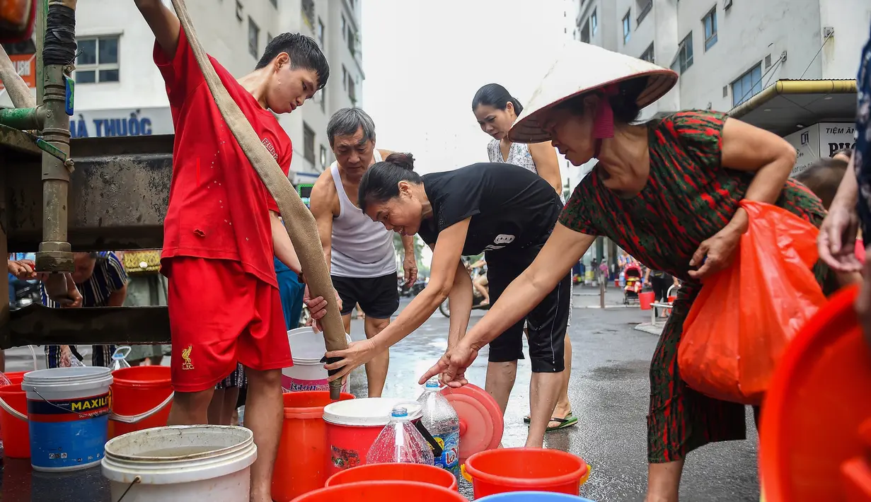 Warga mengisi wadah mereka dengan air dari truk tangki pasokan pemerintah di Hanoi, Vietnam, Kamis (17/10/2019). Pejabat tinggi pemerintah mengonfirmasi bahwa air ledeng di Hanoi tenggara terkontaminasi dengan styrene, suatu zat karsinogenik. (Nhac NGUYEN/AFP)