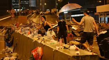 Demonstran membersihkan sampah setelah aksi menolak RUU ekstradisi di Hong Kong (12/6/2019). Aksi tersebut berujung bentrok antara polisi dan warga dimana puluhan ribu orang memblokir jalan-jalan di kota tersebut. (AFP Photo/Hector Retamal)