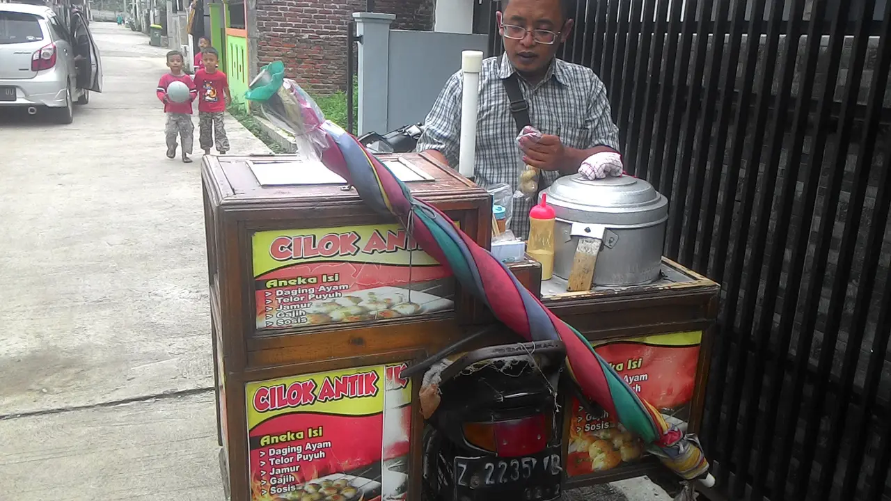 Nampak pedagang cilok keliling tengah melayani pembeli