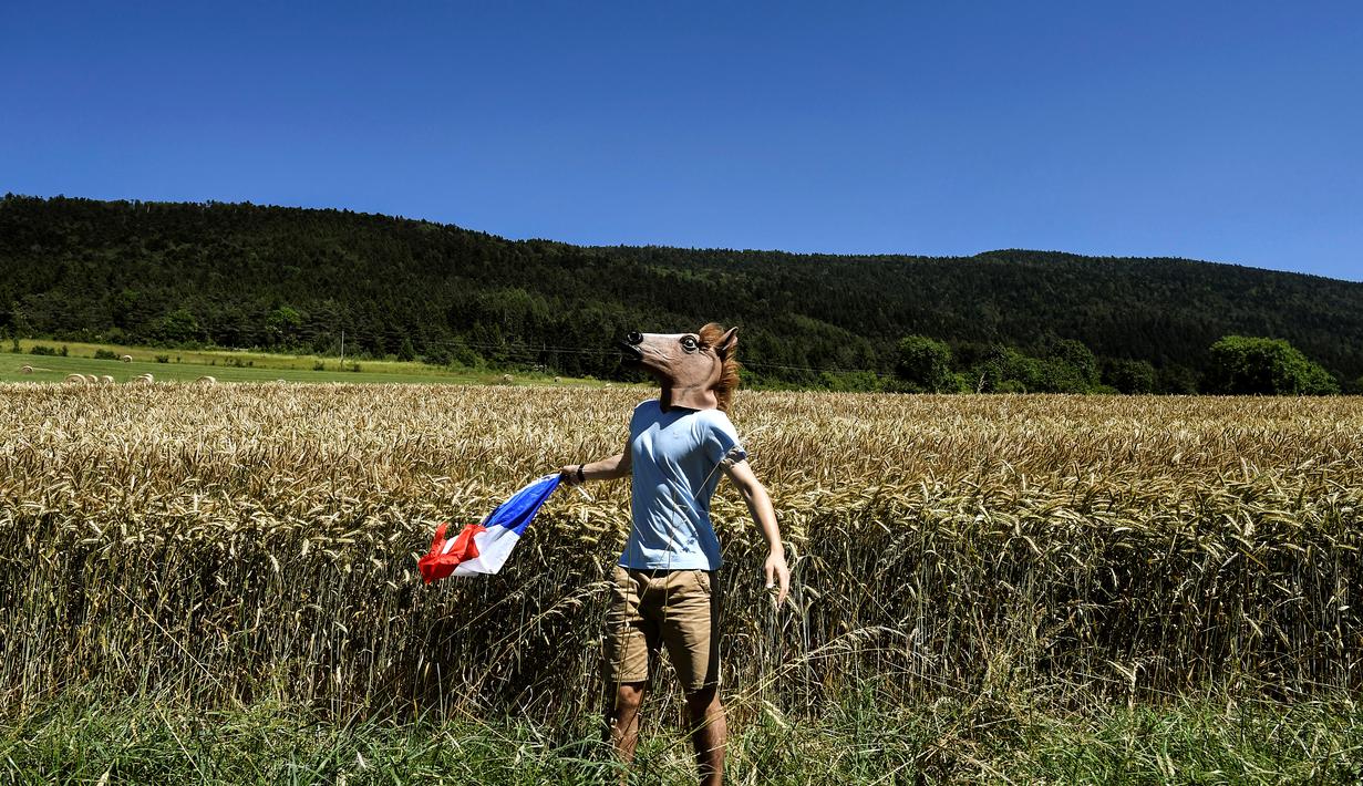 Seorang penonton memakai topeng kuda saat menyambut pebalap di Etape 15 Tour de France antara Bourg-en-Bresse dan Culoz, (17/7/2016). (AFP/Jeff Pachoud)