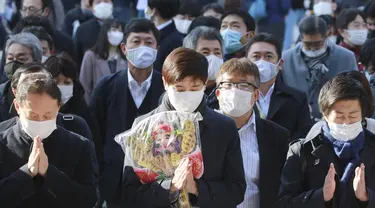 Orang-orang yang mengenakan masker melakukan tradisi doa untuk Tahun Baru pada hari kerja pertama tahun ini di Kuil Kanda Myojin, di Tokyo, Jepang, Senin (4/1/2021).  Orang-orang berdoa untuk mencari keberuntungan dan bisnis yang Makmur. (AP Photo/Koji Sasahara)