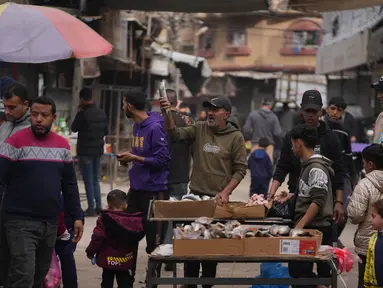 Seorang pedagang Palestina memajang ikan sarden untuk dijual di jalanan pasar lokal di Kota Gaza, Jumat, 19 Desember 2025. Meski kondisi dan situasi masih sangat rapuh akibat kehancuran infrastruktur yang masif akibat serangan Israel sejak Oktober 2023 lalu, dinamika ekonomi di Gaza mulai kembali menggeliat. (AP Photo/Abdel Kareem Hana)