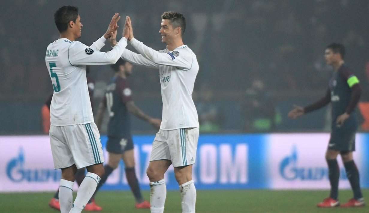 Pemain Real Madrid, Cristiano Ronaldo dan Raphael Varane, merayakan kemenangan atas PSG pada laga Liga Champions di Stadion Parc des Princes, Paris, Selasa (6/3/2018). Madrid berhasil lolos ke delapan besar. (AFP/Christophe Simon)
