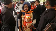 Orang tua dan bayi melewati pemeriksaan sebelum menonton laga Piala AFC 2018 antara Persija Jakarta vs Song Lam Nghe An di Stadion Utama GBK, Rabu (14/3/2018). Panpel menjual sekitar 65.000 lembar tiket. (Bola.com/Surya Bima Mahendarta)