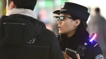 Petugas mengenakan kacamata pintar dengan sistem pengenalan wajah di Stasiun Kereta Zhengzhou East, China (5/2). Kacamata ini memiliki kamera yang tersambung dengan perangkat mirip telepon pintar. (AFP Photo/China Out)