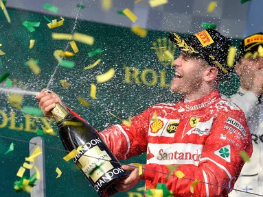 Pembalap Ferrari, Sebastian Vettel menyemprotkan sampanye di atas podium setelah berhasil memenangi balapan GP Australia di Sirkuit Albert Park, Melbourne, Minggu (26/3). Vettel sukses mengasapi rival utamanya Lewis Hamilton. (AP Photo/Andy Brownbill)