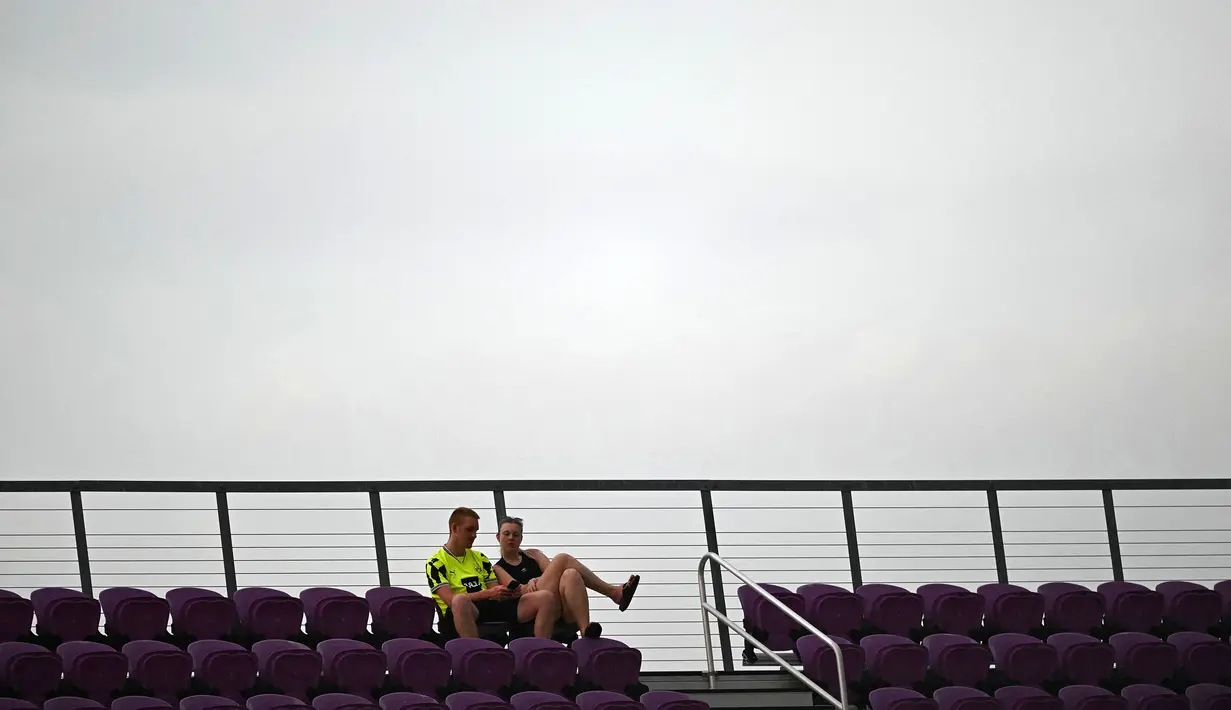 Dua penonton duduk di antara bangku tribune kosong dalam pertandingan Grup F Piala Dunia Antarklub 2025 antara Ulsan HD FC melawan Mamelodi Sundowns FC di Inter&Co Stadium, Orlando, Florida, Amerika Serikat, Rabu (18/06/2025) WIB. (AFP/Patricia De Melo Moreira)