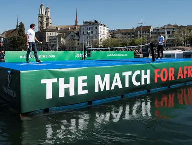 Petenis asal Swiss, Roger Federer (kiri) bertanding melawan petenis asal Inggris, Andy Murray di lapangan kecil di atas sungai Kota Zurich, Senin (10/4). Kedua petenis itu terlibat dalam program amal The Match For Africa 3. (Ennio Leanza/Keystone via AP)
