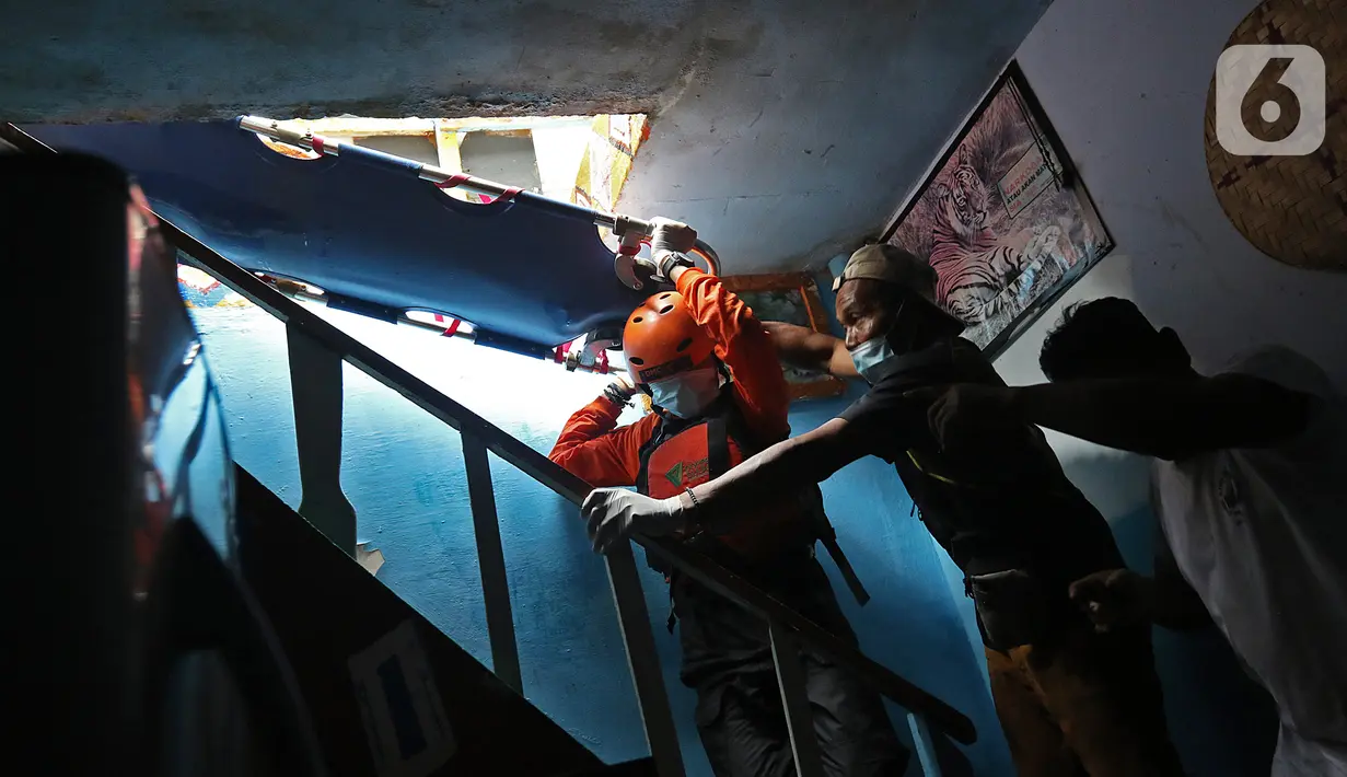 Relawan dan keluarga menurunkan jenazah warga untuk dievakuasi saat banjir melanda kawasan Cipinang Melayu, Jakarta Timur, Jumat (19/2/2021). Seorang nenek (80) meninggal di kediamannya, di lokasi banjir, di RW 04, kawasan tersebut karena sakit dan sudah lanjut usia. (Liputan6.com/Herman Zakharia)