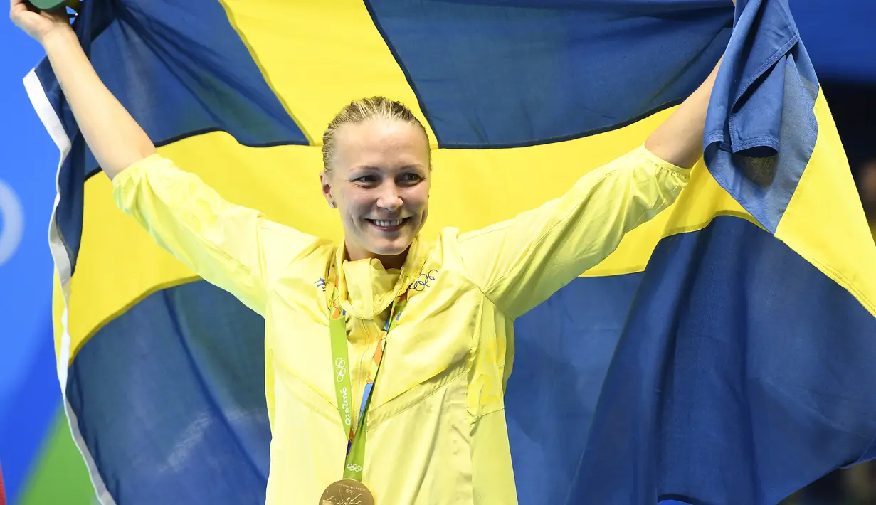Sarah Sjostrom memegang bendera Swedia di atas podium setelah meraih medali emas renang nomor 100 meter gaya kupu-kupu pada Olimpiade 2016 di Rio de Janeiro, Minggu (7/8). Sjostrom memecahkan rekor dunianya atas namanya sendiri (GABRIEL Bouys/AFP)