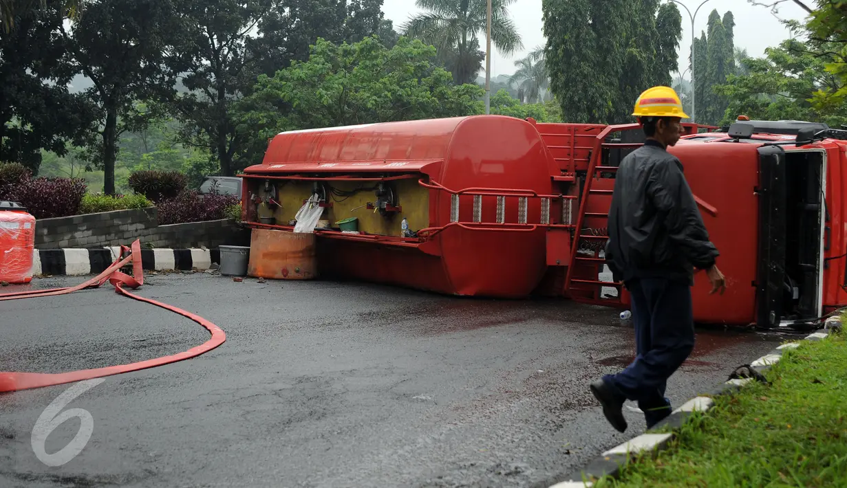 Petugas melintas di depan truk tangki BBM yang terbalik di ruas Jalan Tegar Beriman Kabupaten Bogor, Jumat (15/4/2016). Truk tangki bermuatan 24.000 liter BBM jenis premium terbalik sekitar pukul 05.00 dini hari. (Liputan6.com/Helmi Fithriansyah)