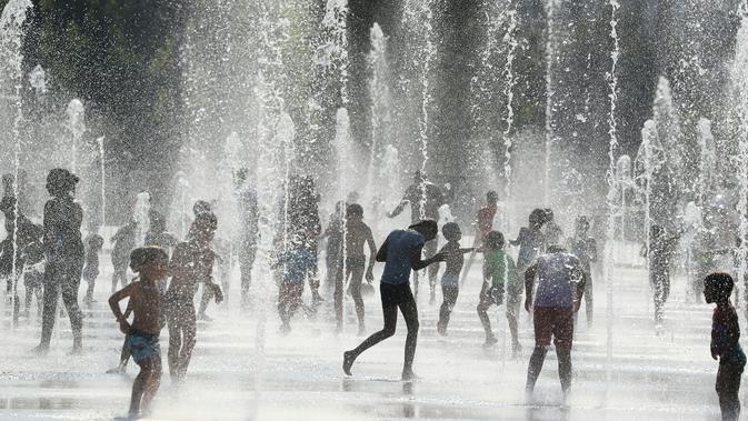 Orang-orang mendinginkan badan di air mancur saat gelombang panas menyapu seluruh Eropa utara di Nice, Prancis, Selasa (31/7). Sebagian wilayah Prancis telah menjadi daerah waspada tinggi karena meningkatnya gelombang panas. (AFP/VALERY HACHE)