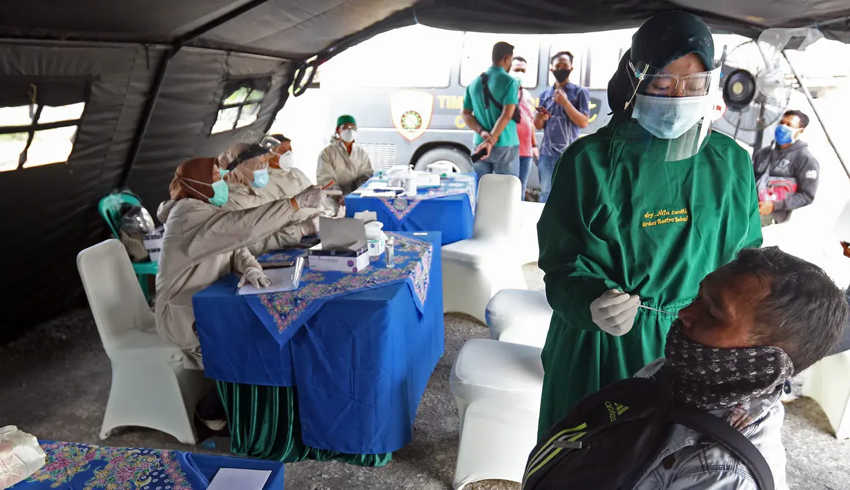 Petugas melakukan swab antigen terhadap pengendara yang melintas di Kedungwaringin, Kabupaten Bekasi, Kamis  (29/4/2021). Satlantas Polres Metro Bekasi melakukan swab antigen dan sosialisasi larangan mudik jelang lebaran di perbatasan Kabupaten Bekasi dan Karawang. (Liputan6.com/Herman Zakharia)