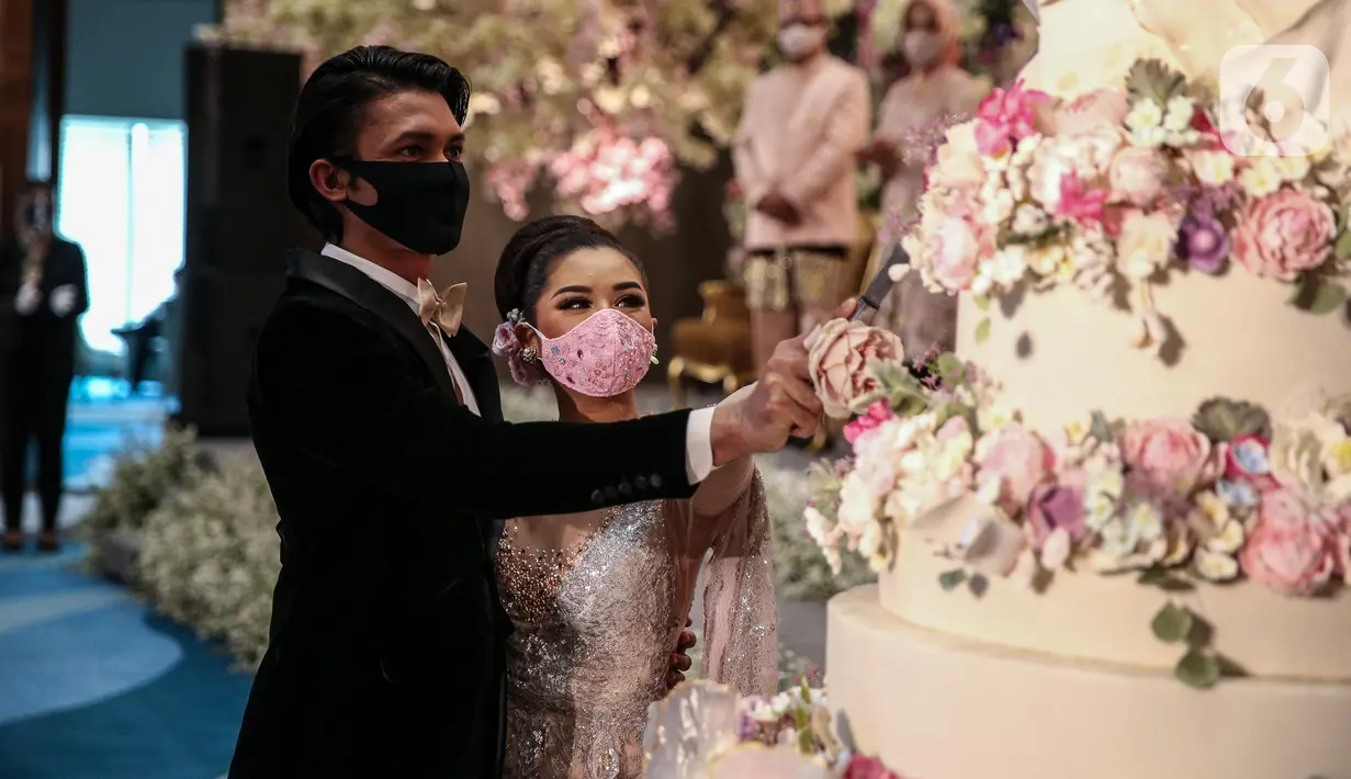 Pengantin memakai masker saat simulasi penerapan protokol kesehatan resepsi pernikahan di era new normal di Jakarta, Kamis (9/7/2020). Kegiatan ini bertujuan untuk mengedukasi masyarakat dalam acara pernikahan guna mencegah penyebaran COVID-19. (Liputan6.com/Faizal Fanani)
