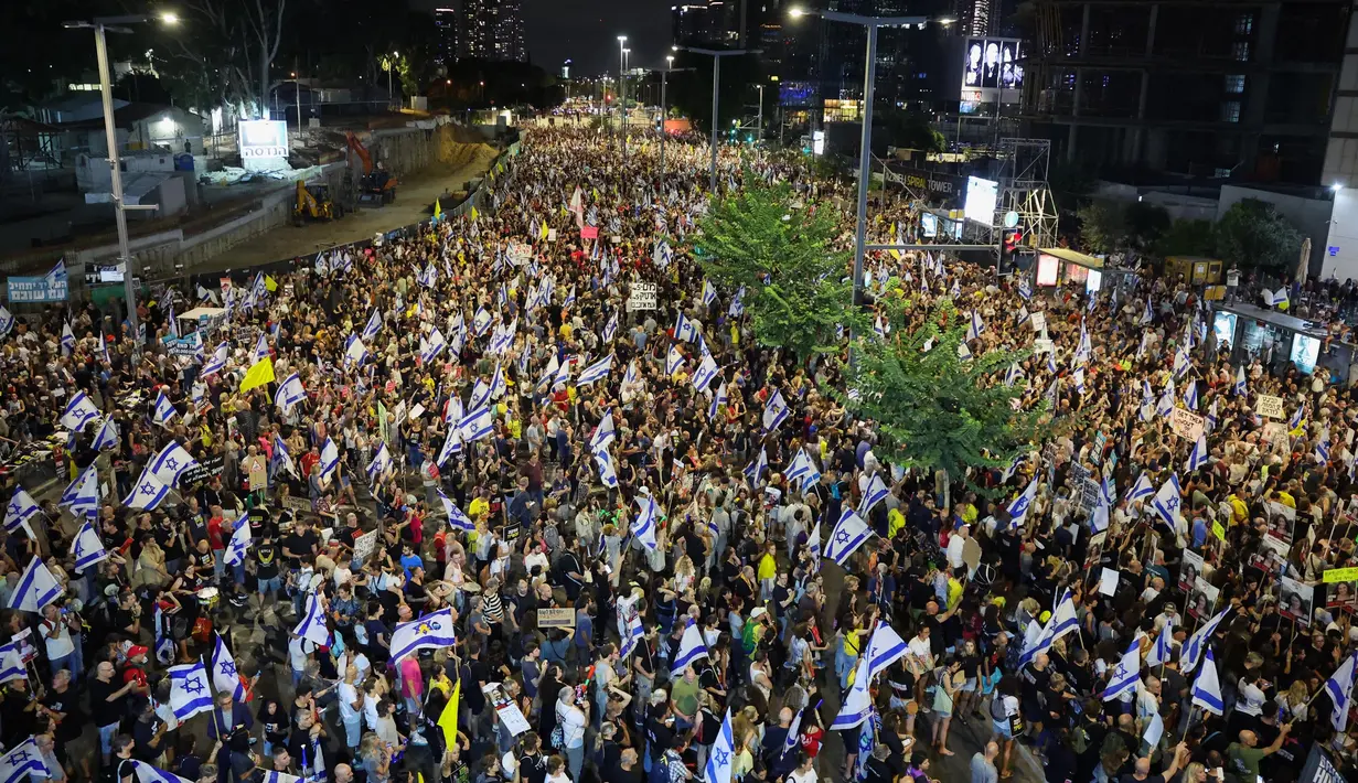 Para pengunjuk rasa mengangkat bendera dan plakat dalam unjuk rasa anti-pemerintah yang menuntut pembebasan warga Israel yang disandera oleh militan Palestina di Gaza sejak Oktober, di depan Kementerian Pertahanan Israel di Tel Aviv pada 14 September 2024. (Jack GUEZ/AFP)