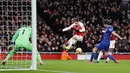 Striker Arsenal, Alexandre Lacazette berusaha memasukan bola dari kawalan bek Chelsea Marcos Alonso selama pertandingan lanjutan Liga Inggris di stadion Emirates di London (19/1). Arsenal menang 2-0 atas Chelsea. (AP Photo/Frank Augstein)