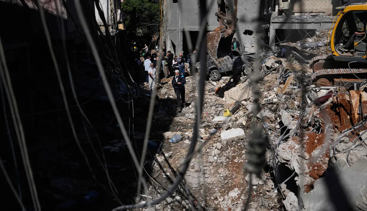 Dua jembatan di Sungai Litani yang menghubungkan wilayah Sohmor dan Machghara di Bekaa Barat, Lebanon, dilaporkan hancur dihantam serangan udara Israel. Tampak dalam foto, orang-orang berkumpul saat sebuah ekskavator membersihkan puing-puing di lokasi serangan Israel pada Minggu 5 April 2026 terhadap sebuah bangunan di lingkungan Jnah, Beirut, Lebanon, Senin 6 April 2026. (AP Photo/Hassan Ammar)