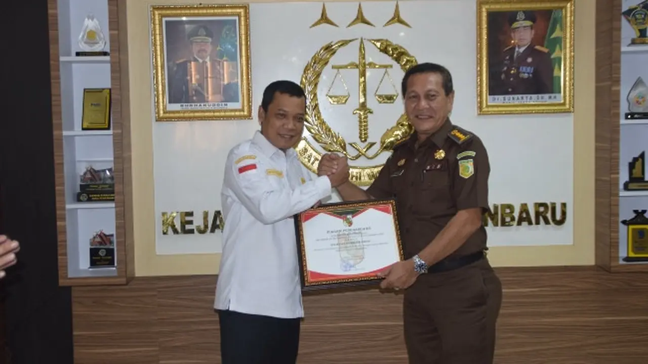 Pj Wali Kota Muflihun memberikan penghargaan kepada Plt Kepala Kejari Pekanbaru terhadap pemulihan keuangan negara Rp5,2 miliar dari pengelolaan sampah.
