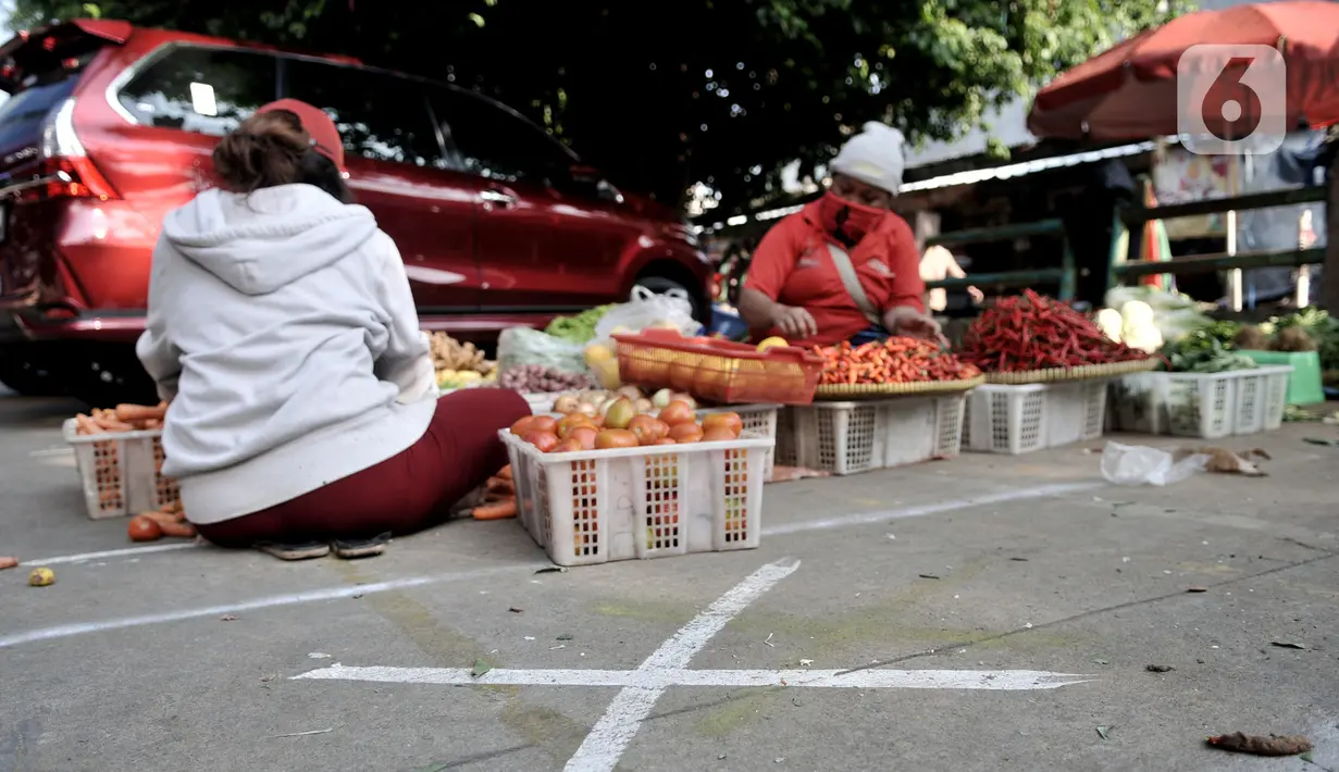 Pedagang berjualan dekat tanda ‘X‘ yang digunakan sebagai pembatas physical distancing di Pasar Perumnas Klender, Jakarta, Kamis (18/6/2020). Selain sistem ganjil genap kios, pengelola pasar menerapkan physical distancing antarlapak untuk mencegah penularan COVID-19. (merdeka.com/Iqbal S. Nugroho)