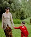 Asmirandah tampil elegan mengenakan kebaya warna nude dengan aksen kancing depan dipadukan bawahan kain batik lilit. Putrinya Chloe pun menggemaskan tampil dengan kebaya brokat merah dipadukan kain batik serasi dengan sang mamah. [@asmirandah89]