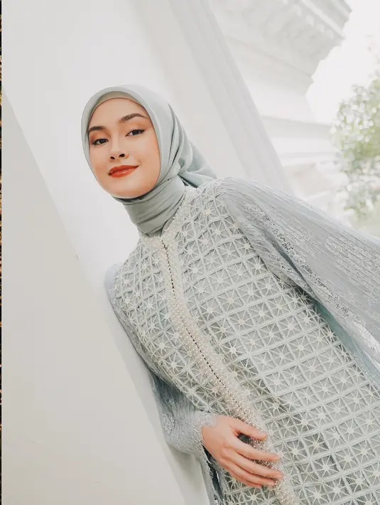 Caitlin Halderman tak kalah anggun dengan hijab pashmina biru pastel yang elegan. Ia mengenakan gaun panjang bertekstur lace dengan motif geometris dan detail sulaman bintang putih yang memberi kesan mewah. Pilihan busana Caitlin memancarkan aura elegan, rapi, dan sangat menawan. (Liputan6.com/IG/@caitlinhalderman)