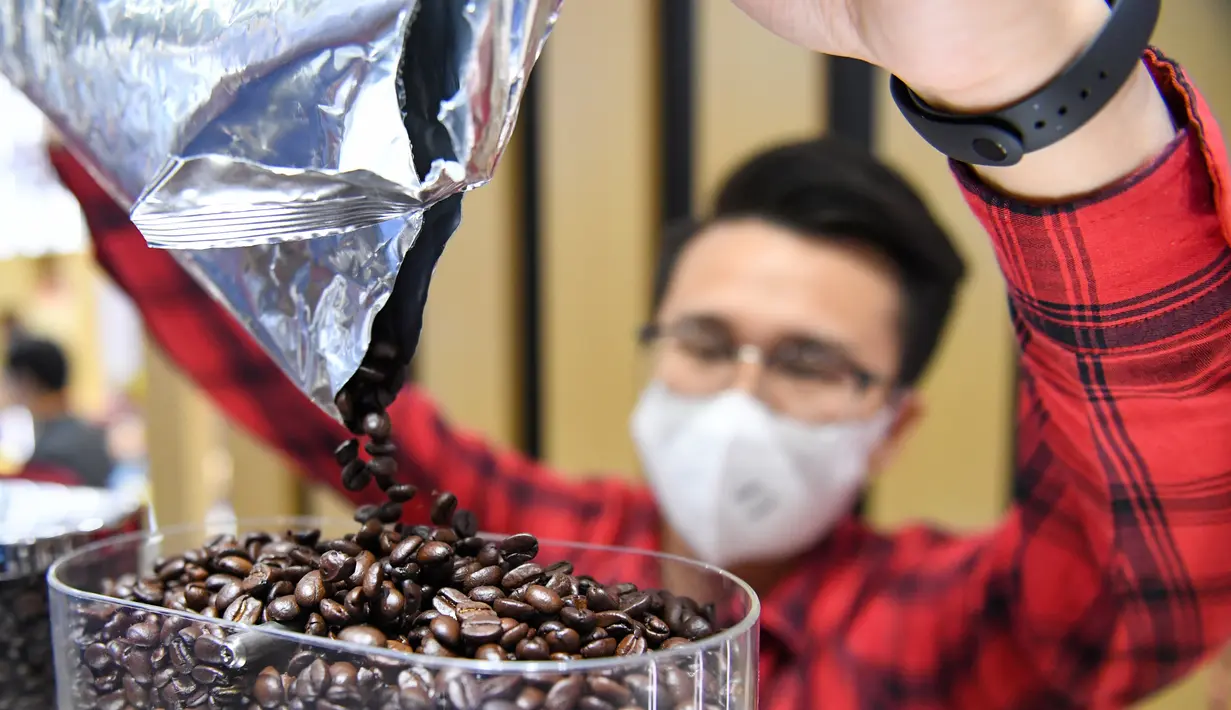Seorang staf menuang biji kopi ke dalam mesin pembuat kopi di stan jaringan restoran cepat saji asal Kanada, Tim Hortons, di area ekshibisi Produk Makanan dan Pertanian Pameran Impor Internasional China (China International Import Expo/CIIE) ketiga di Shanghai, China timur (5/11/2020). (Xinhua/Chen