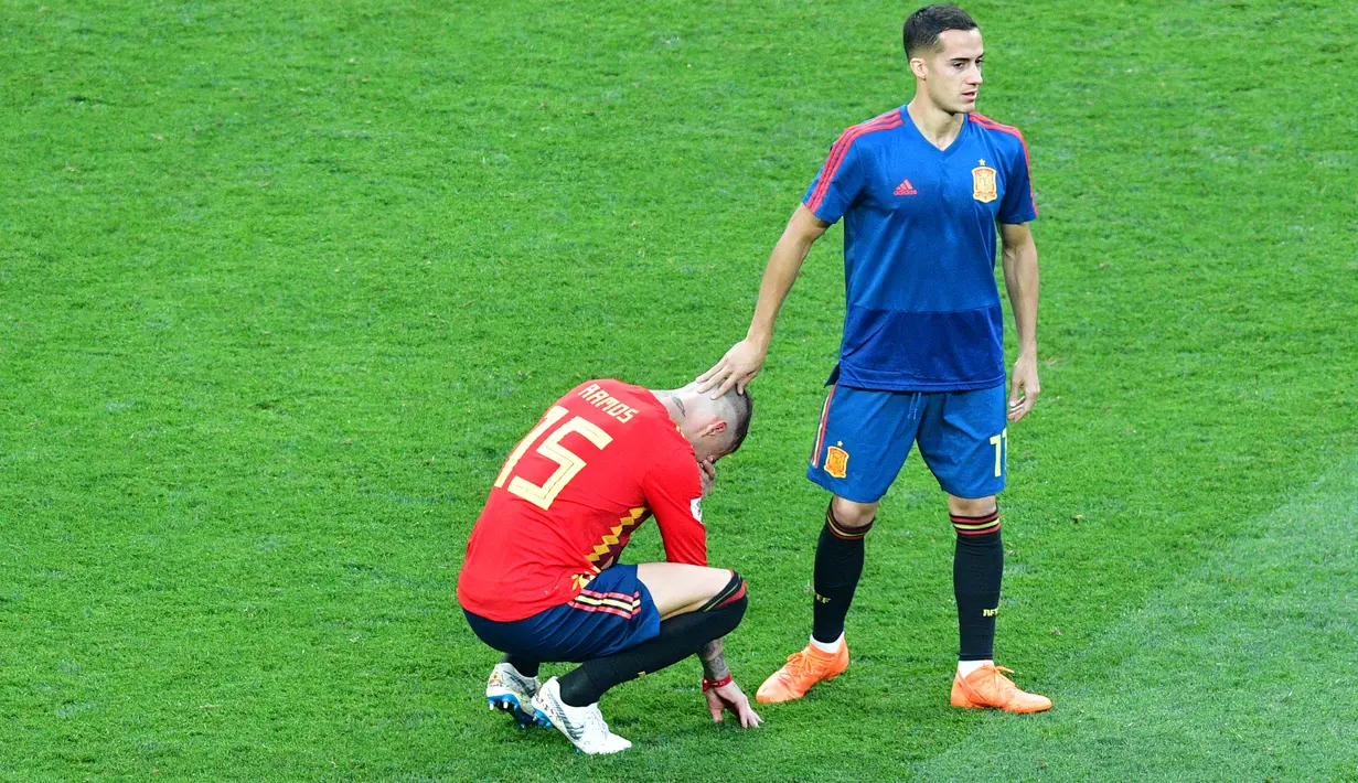 Gelandang Spanyol, Lucas Vazquez menenangkan Sergio Ramos yang menangis usai pertandingan melawan Rusia di babak 16 besar Piala Dunia 2018 di Stadion Luzhniki, Moskow, Rusia (1/7). Spanyol kalah lewat adu penalti atas Rusia 3-4. (AFP Photo/Mladen Antonov)
