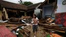 Seorang gadis menggendong bayi berjalan di dekat puing-puing di daerah yang dilanda tsunami di Carita, Banten, Kamis, (27/12). (AP Photo/Achmad Ibrahim)