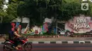 Lukisan mural dari tangan PPSU yang memanfaatkan tanaman merambat hijau menghiasi bangunan tua di kawasan Jalan Malaka, Jakarta, Selasa (29/8/2023). (Liputan6.com/Johan Tallo)