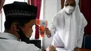 Seorang siswa sekolah menengah pertama menjalani pemeriksaan suhu tubuh sebelum menerima dosis vaksin Sinovac pada acara vaksinasi virus corona COVID-19 di Blang Bintang, Provinsi Aceh, 21 September 2021. (CHAIDEER MAHYUDDIN/AFP)