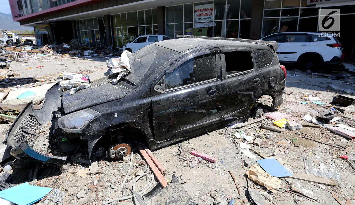 Sebuah mobil Datsun menjadi incaran jarahan korban gempa dan tsunami di Palu Grand Mal, Palu, Jumat (5/10). Warga korban gempa bumi mengambil ban dan interior mobil. (Liputan6.com/Fery Pradolo)