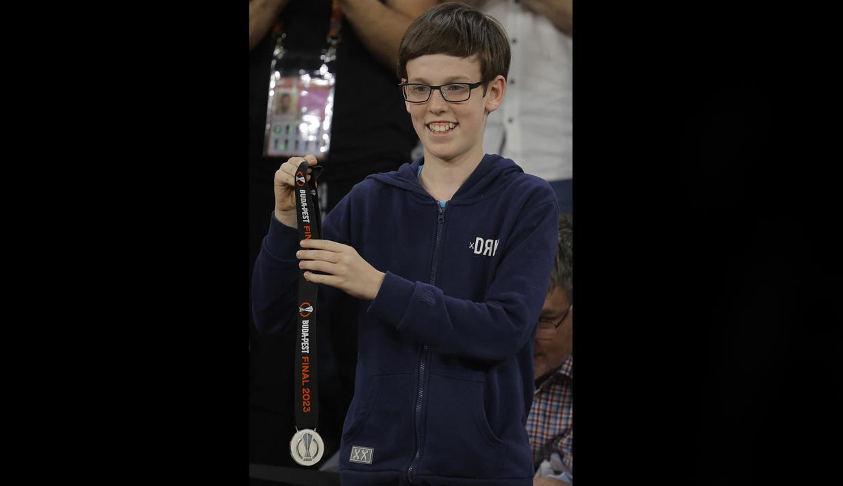 Seorang suporter cilik AS Roma menunjukkan medali yang diberikan Jose Mourinho setelah pertandingan final Liga Europa 2022/2023 yang berlangsung di Stadion Puskas Arena, Hungaria, Jumat (01/06/2023) dini hari WIB. (AFP/Odd Andersen)