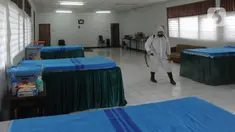 Petugas gugus tugas Covid-19 RW 03 menyemprotkan desinfektan pada tempat tidur untuk isolasi mandiri di Gedung Sasana Krida Karang Taruna, Kelurahan Pondok Labu, Jakarta, Selasa (19/1/2020). Gedung itu disulap oleh warga setempat untuk dijadikan tempat isolasi mandiri. (merdeka.com/Arie Basuki)