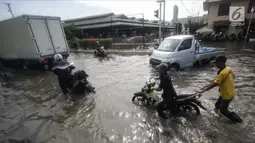 Pengendara mendorong motornya saat melintasi banjir rob di kawasan Muara Baru, Jakarta, Rabu (6/11). Banjir rob yang menggenangi kawasan ini setinggi 50 cm hingga 70 cm. (Liputan6.com/Faizal Fanani)