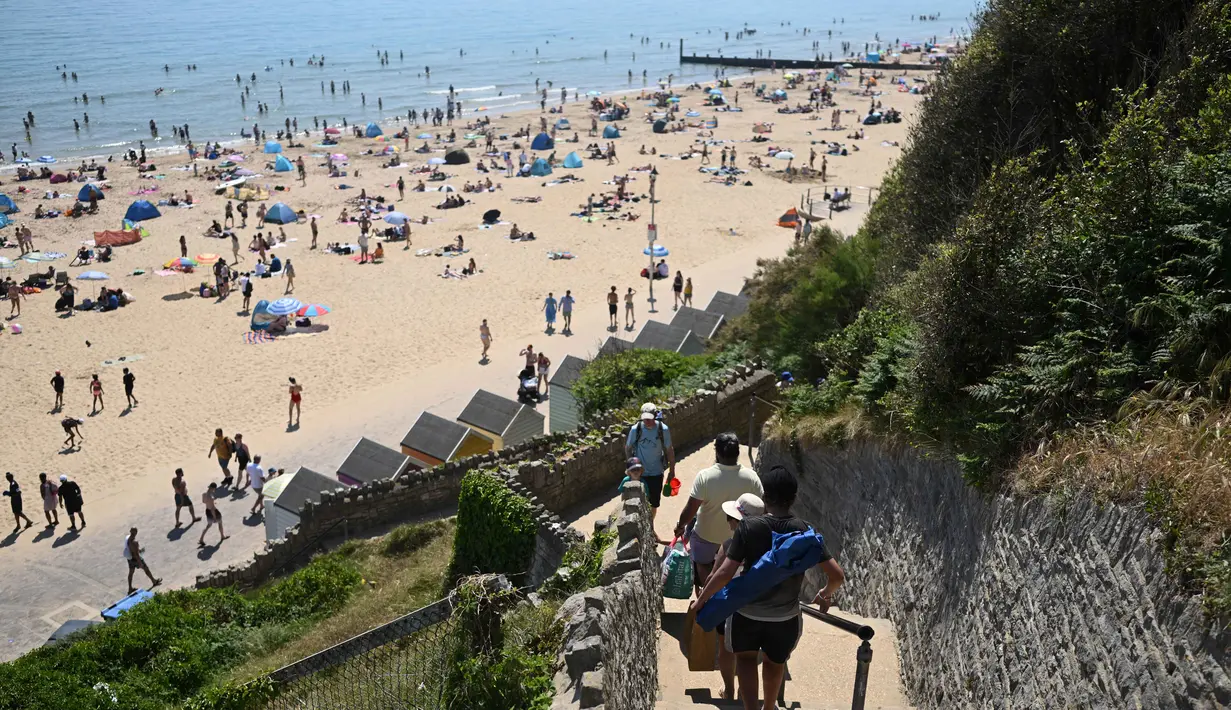 Orang-orang menuruni tangga menuju Pantai Bournemouth, Selatan Inggris pada Selasa 26 Mei 2026, saat kondisi gelombang panas menyebar ke sebagian wilayah tenggara Inggris dan London. (JUSTIN TALLIS/AFP)
