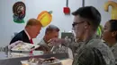 Presiden Amerika Serikat Donald Trump (kiri) mengambil makan malam saat mengunjungi Pangkalan Udara Bagram, Afghanistan, Kamis (28/11/2019). Kunjungan dadakan Trump pada hari Thanksgiving tersebut mengejutkan pasukan AS yang bertugas di Afghanistan. (AP Photo/Alex Brandon)