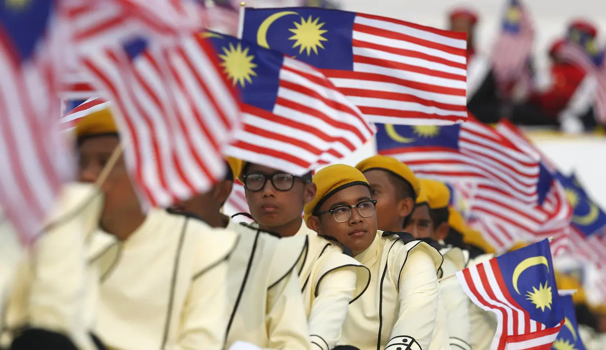 Warga mengikuti parade kemerdekaan sambil mengibarkan bendera Malaysia saat perayaan Hari Kemerdekaan ke-58 di Kuala Lumpur, Senin (31/8/2015).  Perayaan kemerdekaan kali ini dilakukan di tengah desakan mundur kepada PM Najib. (REUTERS/Olivia Harris)