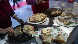 Relawan mengantarkan potongan pizza yang dibuat oleh master pizza selama Kejuaraan Pizza Argentina di Buenos Aires, Argentina, Selasa (7/6/2022). Pemenang yang terpilih sebagai “Great Argentine Champion” akan menjadi bagian dari tim Argentina di Kejuaraan Pizza Dunia 2023 di Parma (Italia). (AP Photo/Rodrigo Abd)
