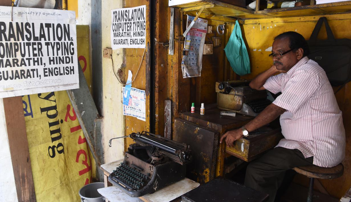 Seorang juri ketik menunggu pelanggan di kios ketik pinggir jalan di Mumbai, India (6/7). (AFP Photo/Indranil Mukherjee)
