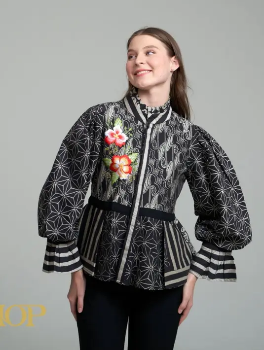 Blouse Capia, berwarna dasar hitam dengan bordir motif bunga yang cantik. Koleksi batik cap satu ini merupakan kombinasi bordir dari Batik by HOP. Didesain dengan lengan panjang model balon, blouse ini memadukan keanggunan batik tradisional dengan sentuhan modern yang memikat. [Dok/instagram/batikbyhop.id]
