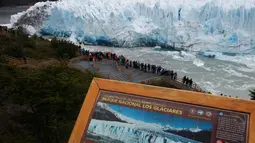 Wisatawan menyaksikan bongkahan es yang runtuh dari Perito Moreno Glacier di Taman Nasional Los Glaciares, Argentina, Sabtu (10/3). Runtuhnya es dari gletser merupakan hal yang banyak ditunggu oleh wisatawan yang berkunjung. (Walter Diaz/AFP)