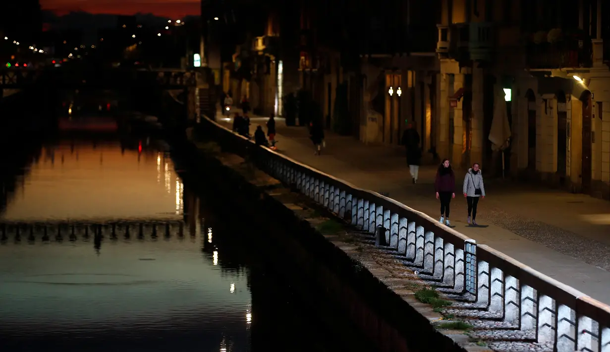 Beberapa orang berjalan di Kanal Naviglio Grande, Milan, Italia, Selasa (10/3/2020). Sepinya salah satu tempat favorit bagi kehidupan malam tersebut imbas dari penerapan aturan lockdown yang diambil Italia demi mencegah penyebaran virus corona (COVID-19). (AP Photo/Antonio Calanni)