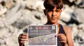 Seorang anak laki-laki memegang salah satu selebaran yang dijatuhkan oleh militer Israel di Kota Gaza, yang menyerukan evakuasi ke selatan menuju al-Mawasi, pada 9 September 2025. (Omar AL-QATTAA/AFP)