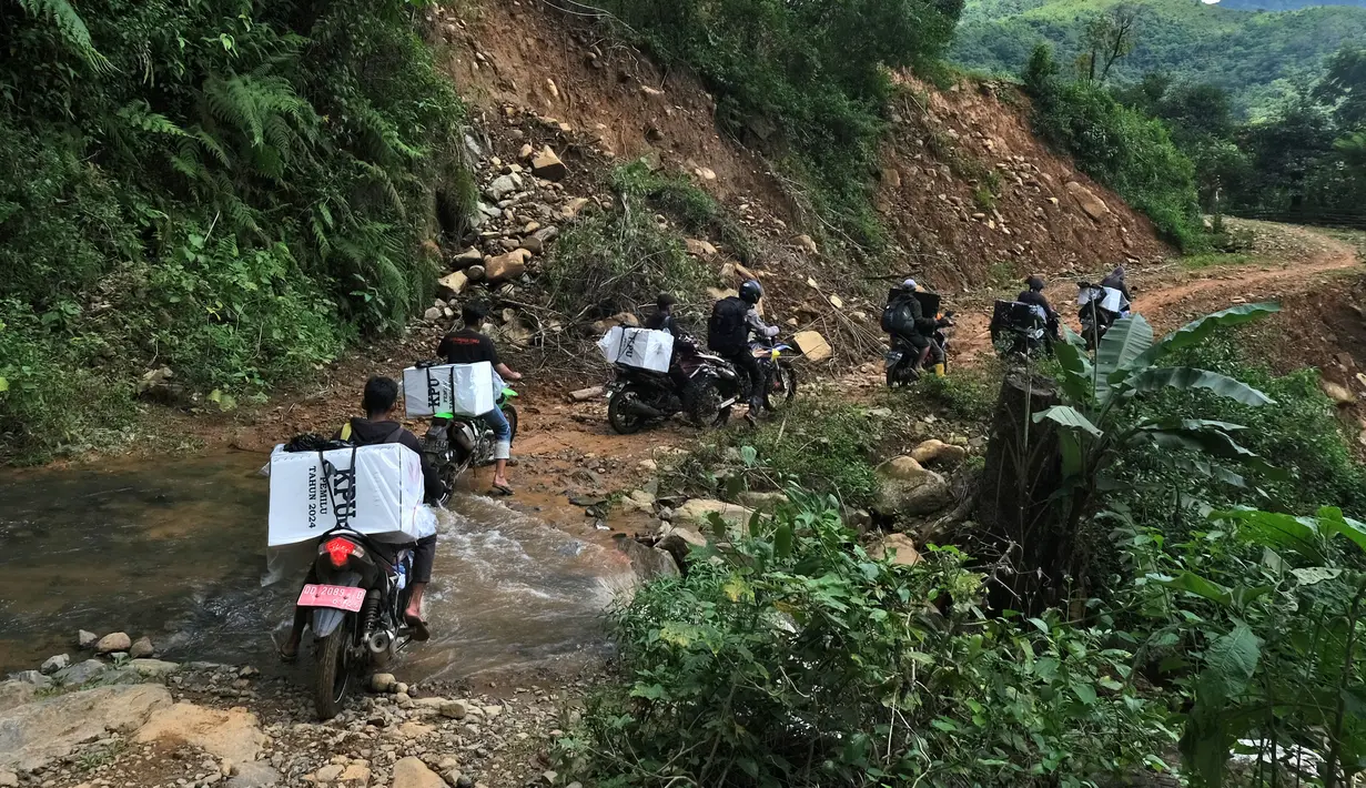 Petugas pemilu membawa kotak suara dan perlengkapan pemilu lainnya dengan sepeda motor untuk didistribusikan ke TPS di desa-desa terpencil menjelang pemilu 14 Februari di Maros, Sulawesi Selatan, Selasa, 13 Februari 2024. (AP Photo/Masyudi S. Firmansyah)