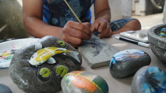 Okky Heryawan atau Mang Obe sedang mengerjakan lukisan di atas batu. (Liputan6.com/Huyogo Simbolon)