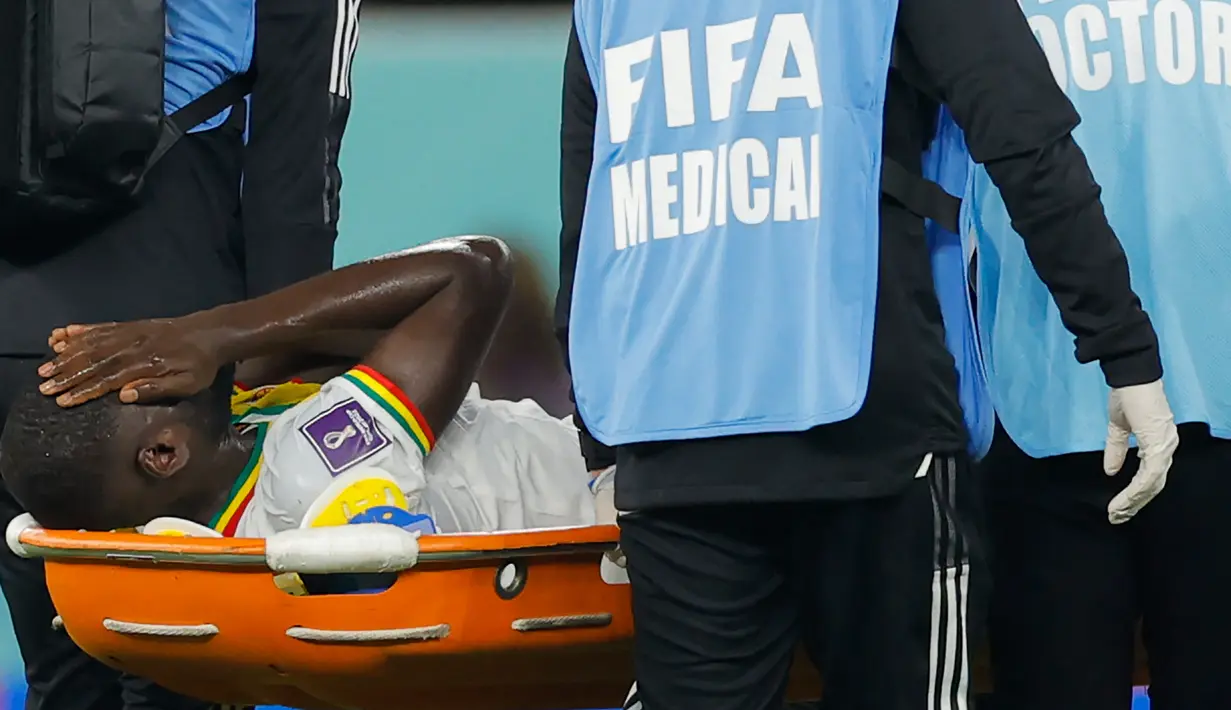 Reaksi gelandang Senegal Cheikhou Kouyate saat dibawa mengguakan tandu setelah mengalami insiden dengan gelandang Belanda, Frenkie de Jong pada pertandingan kedua Grup A Piala Dunia 2022 di Stadion Al-Thumama di Doha, Senin (21/11/2022). Tim medis coba memberi pertolongan kepada Cheikhou Kouyate, namun, rasa sakit yang dirasakan membuatnya harus menepi. (Odd ANDERSEN / AFP)